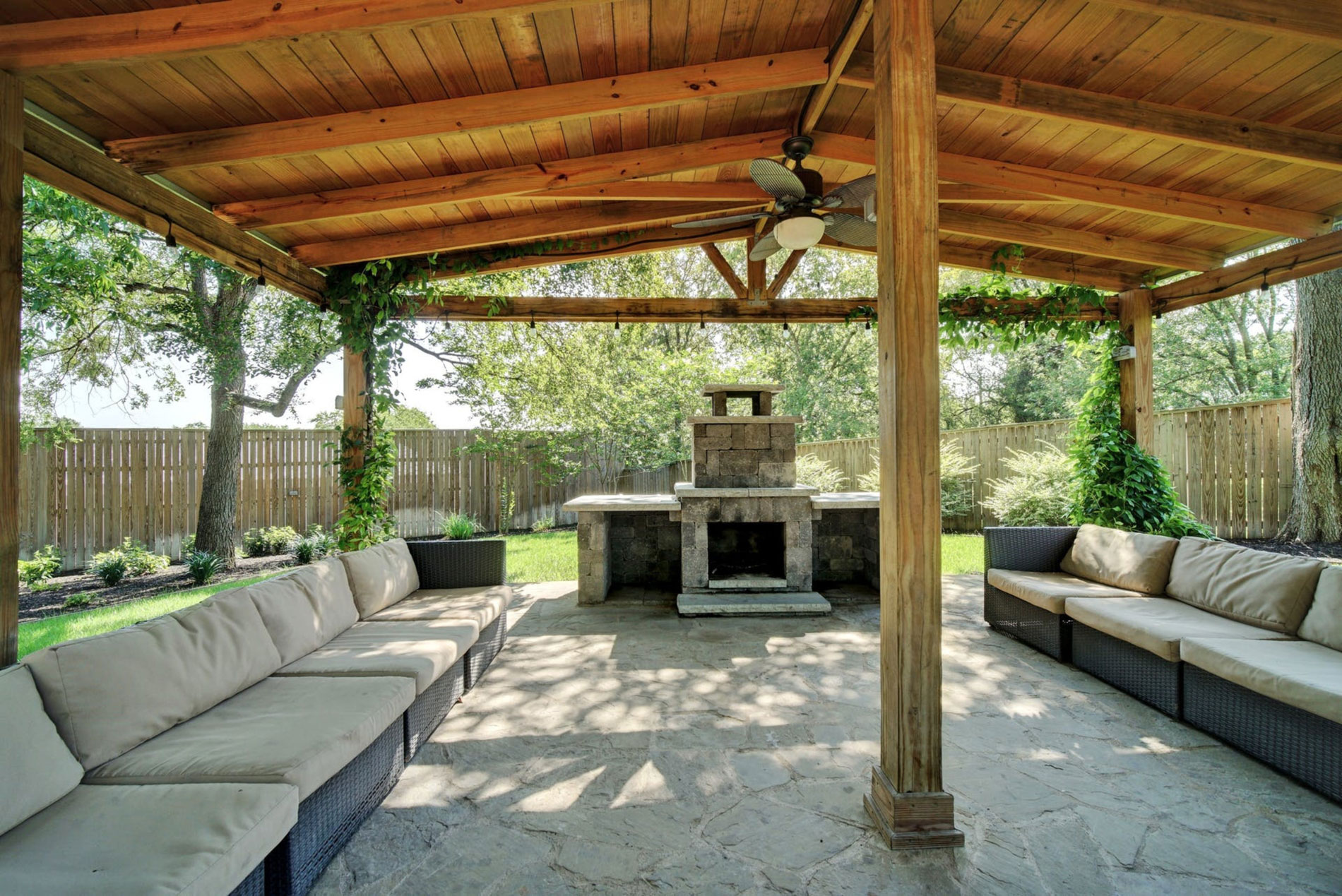 Shaded patio with sofas and a stone fireplace at Legacy Texas.