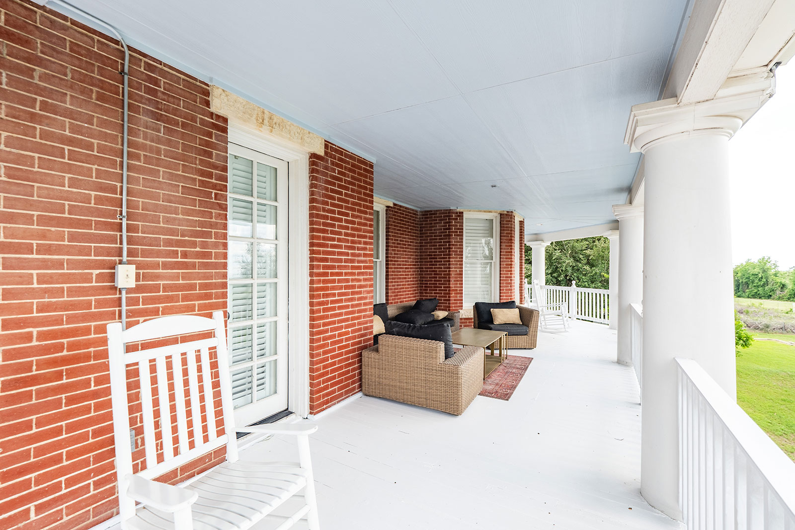 Covered porch with a rocking chair and wicker seating at The Pearl.